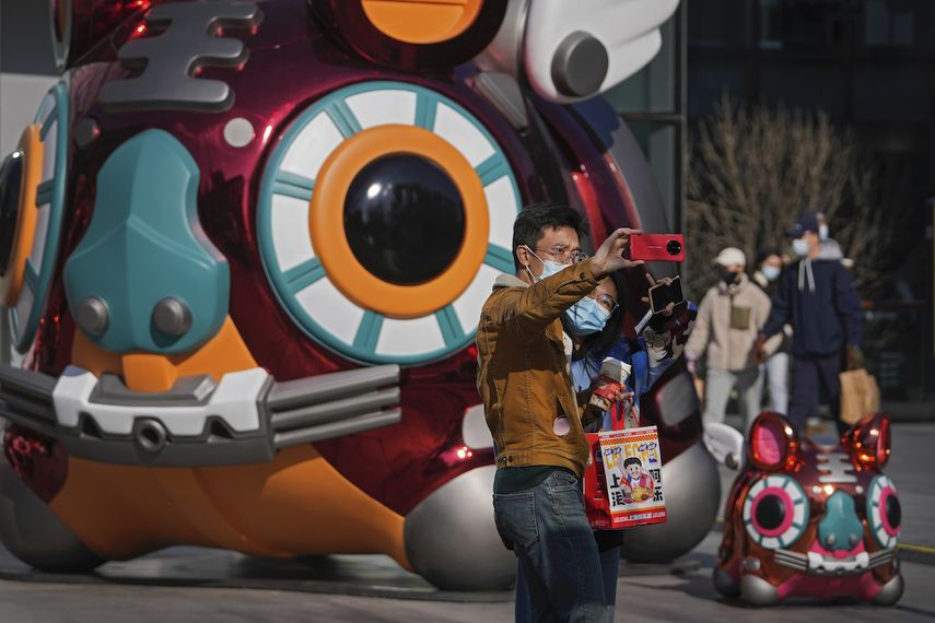 Una pareja con mascarilla para evitar contagios del coronavirus se hace una foto con un tigre robótico colocado como decoración en un centro comercial de Pekín, la víspera del Año Nuevo Lunar, el lunes 31 de enero de 2022.&nbsp;