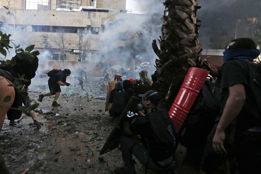 Manifestantes antigubernamentales son rociados por un ca&ntilde;&oacute;n de agua de la polic&iacute;a durante enfrentamientos en Santiago, Chile, el viernes 13 de diciembre de 2019.