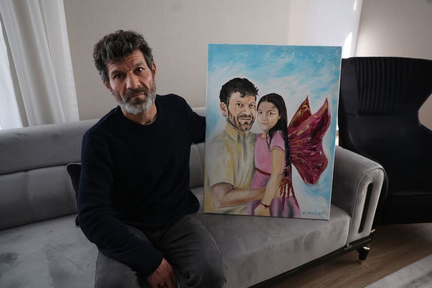 El padre turco Mesut Hancer, posa y sostiene una pintura que lo representa a él y a su hija Irmak en su apartamento en Ankara el 25 de febrero de 2023, mientras su familia intenta reconstruir, luego de perder a su hija Irmak, de 15 años, en el terremoto que devastó el región sureste de Turquía.