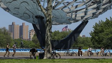 Corredores y ciclistas utilizan mascarillas durante la pandemia del coronavirus mientras pasan el Unisphere, el martes 26 de mayo de 2020.&nbsp;