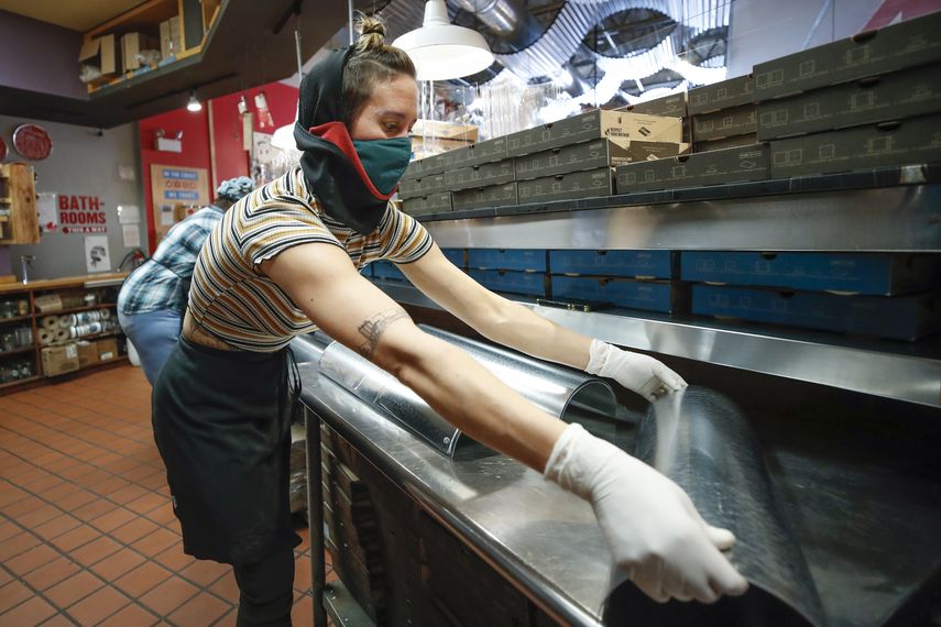 Una empleado dobla láminas de metal en una pizzería.