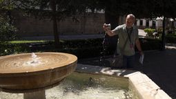 Un hombre sumerge su sombrero en una fuente para refrescarse en Ronda, en el sur de España, durante la primera ola de calor del verano, el 2 de julio de 2025.