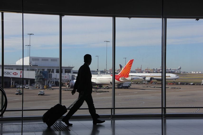 Un hombre camina junto a las ventanas de cristal de un aeropuerto.