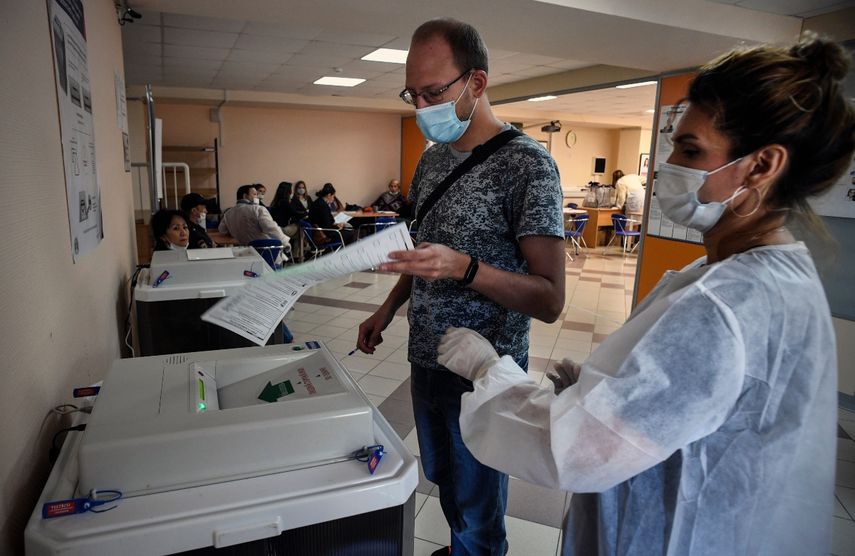 Un hombre deposita su voto en un colegio electoral en Novosibirsk el 13 de septiembre de 2020, mientras lo ayuda un miembro de una comisi&oacute;n electoral local con una m&aacute;scara de protecci&oacute;n. Los rusos votan en las encuestas regionales eclipsados por el envenenamiento del principal l&iacute;der de la oposici&oacute;n Alexei Navalny, una crisis econ&oacute;mica agravada por el coronavirus y las grandes protestas en algunas regiones.