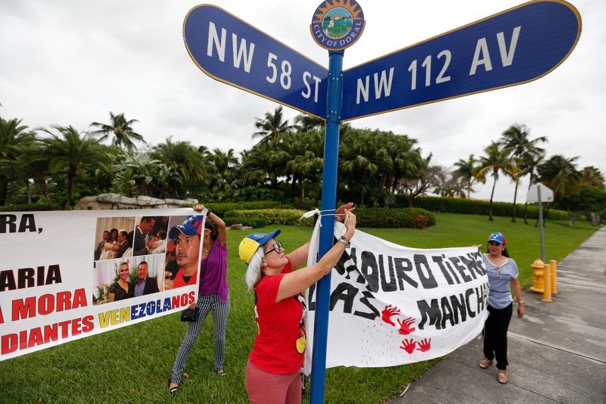 En esta foto del 24 de mayo de 2017, los manifestantes cuelgan una pancarta afuera de una comunidad cerrada donde se cree que un presunto testaferro del prominente gobernador chavista Gregorio Vielma Mora vive con su esposa, la reina de belleza, en un suburbio de Miami conocido como Little Venezuela, en Doral. , Florida.&nbsp;