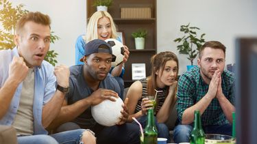 Grupo de amigos observan un evento deportivo por televisión