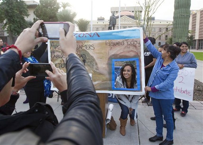Erika Andiola se toma una foto en un cartel que simula ser una licencia de manejo frente al Congreso estatal de Arizona, en Phoenix, el 17 de diciembre de 2014.(AP) 