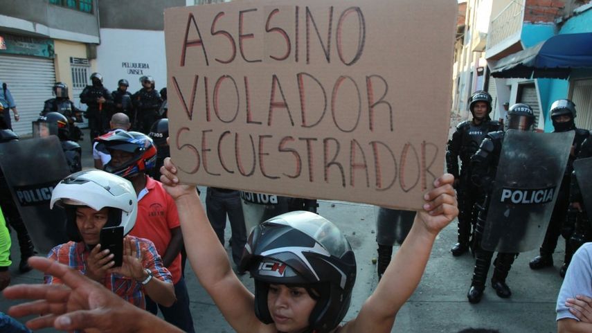 Una mujer muestra una pancarta en el lugar donde el candidato a la presidencia por el partido de las FARC, Rodrigo Londoño, pretendía asistir a un acto de campaña.