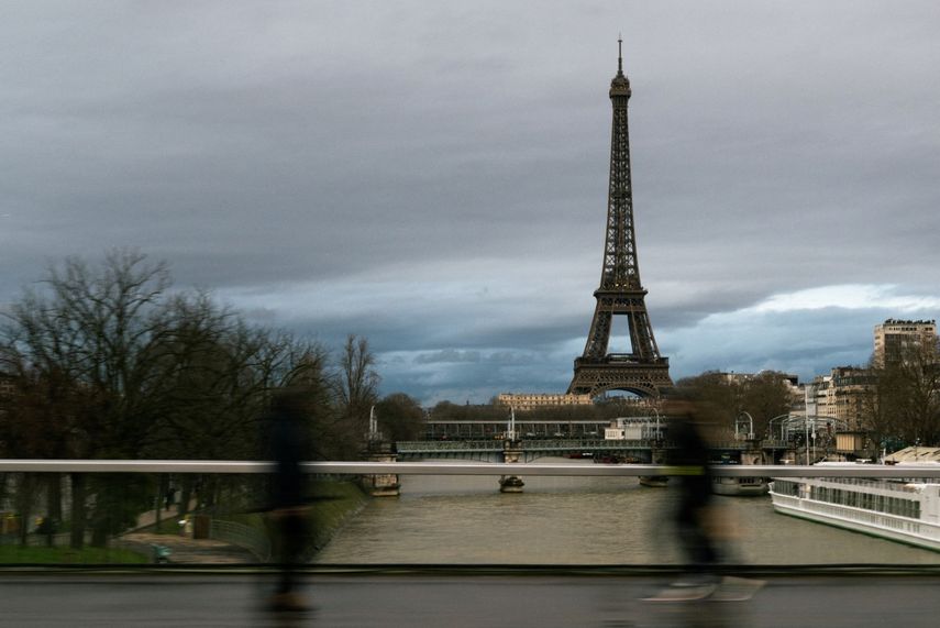 Los peatones caminan por el puente Grenelle-Cadets de Saumur con la Torre Eiffel al fondo bajo un cielo nublado en París, el 26 de enero de 2025.&nbsp;