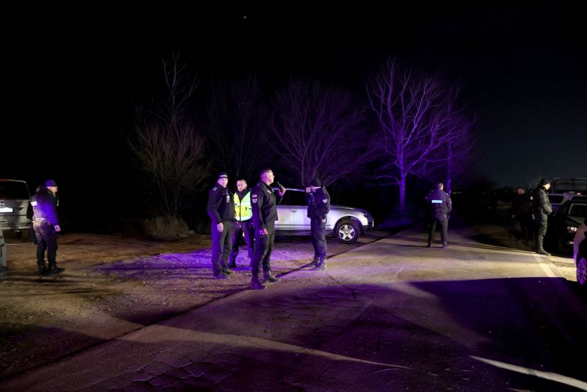 Varios policías montan guardia en Lokorsko, cerca de Sofía, Bulgaria, la noche del viernes 17 de febrero de 2023, luego de que encontraron un camión abandonado que contenía los cuerpos de 18 migrantes, que parecían haber muerto asfixiados dentro de un compartimento secreto bajo una carga de madera.