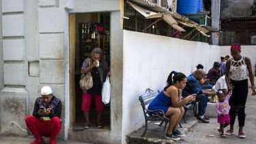 Gente navega en internet en sus teléfonos móviles junto a una plaza en La Habana, Cuba.