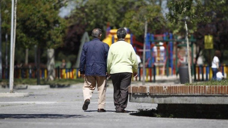 Dos adultos mayores caminan por un parque.