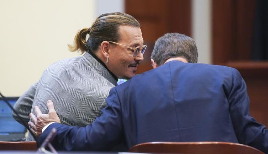 El actor Johnny Depp habla con un miembro de su equipo legal en el Tribunal de Circuito del Condado de Fairfax, el jueves 19 de mayo de 2022 en Fairfax, Virginia.&nbsp;