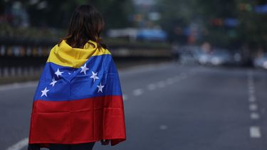 Una mujer envuelve su cuerpo en una bandera venezolana durante una manifestación contra el régimen de Nicolás Maduro en Caracas, Venezuela.
