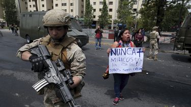 Una mujer protesta junto a un soldado en Santiago, Chile, s&aacute;bado 19 de octubre de 2019. El presidente Sebasti&aacute;n Pi&ntilde;era declar&oacute; el estado de emergencia tras una noche de disturbios.&nbsp;