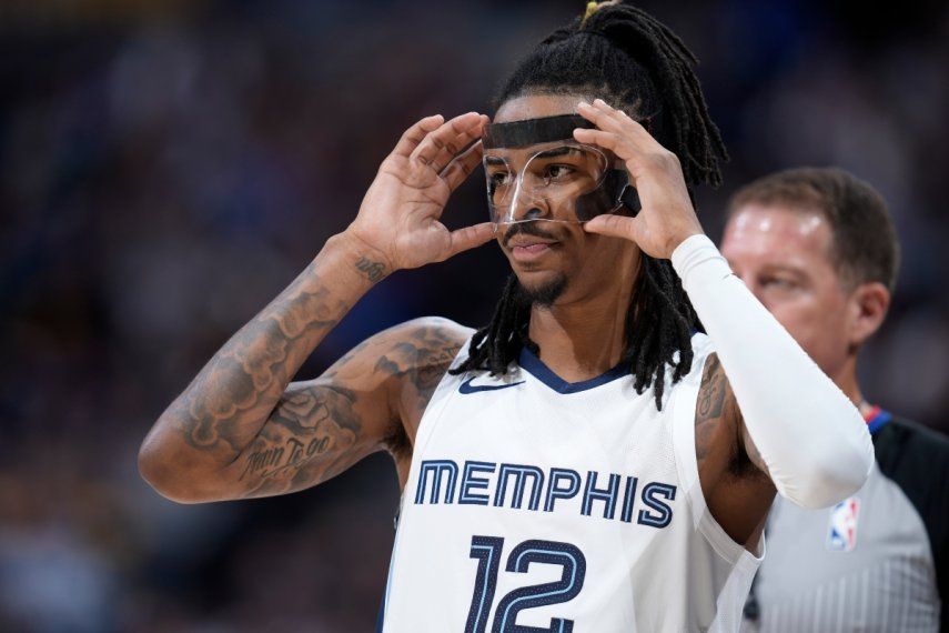 En foto del 3 de marzo del 2023, el base de los Grizzlies de Memphis, Ja Morant, ajusta su máscara en el duelo ante los Nuggets de Denver.