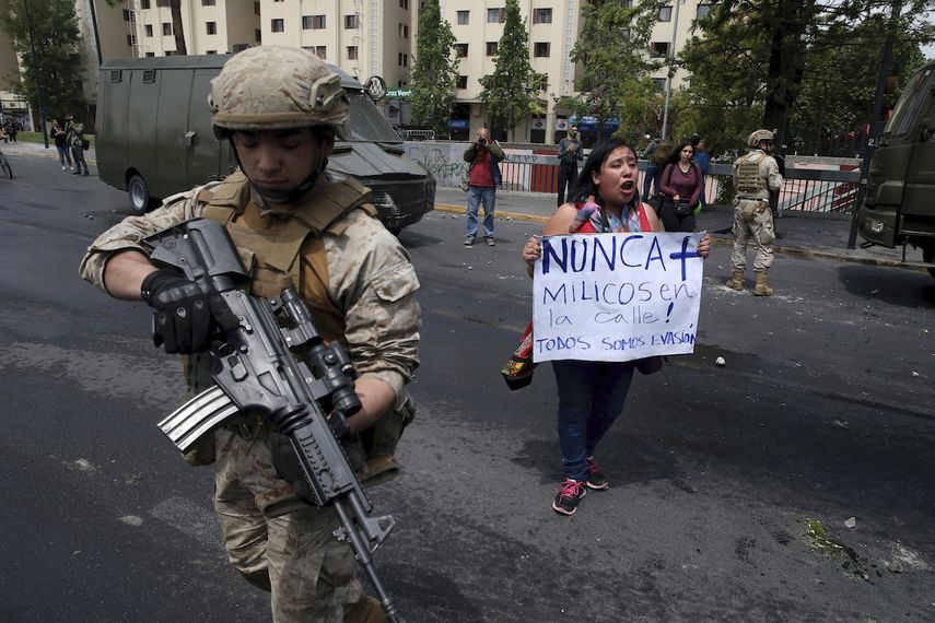 Una mujer protesta junto a un soldado en Santiago, Chile, s&aacute;bado 19 de octubre de 2019. El presidente Sebasti&aacute;n Pi&ntilde;era declar&oacute; el estado de emergencia tras una noche de disturbios.&nbsp;