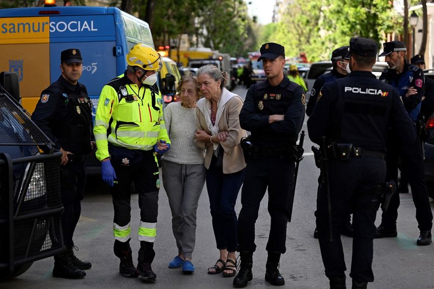 Un socorrista asiste a dos vecinos, ya que los servicios de emergencia buscan a dos personas desaparecidas tras una fuerte explosión que hirió a 17 personas en el barrio de Salamanca de Madrid, el 6 de mayo de 2022.