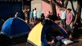 Los migrantes, muchos de ellos venezolanos, se paran junto a sus tiendas mientras esperan para abordar un autobús que los llevará a la frontera entre Nicaragua y Honduras frente a una terminal de autobuses en Managua.