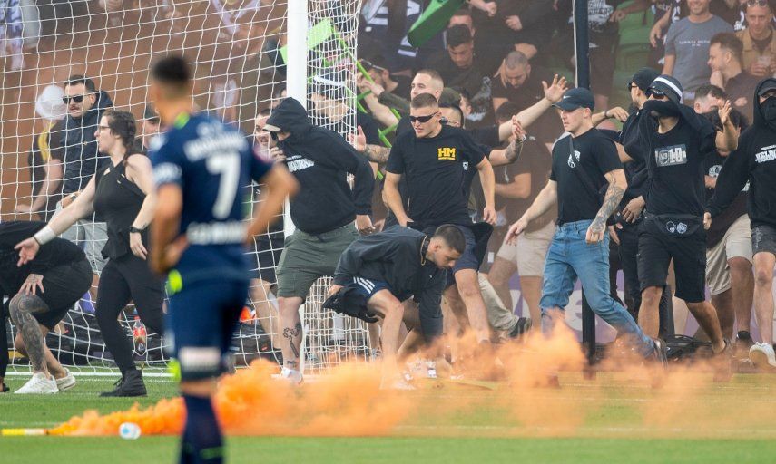 Fans del equipo Melbourne Victory invaden la cancha durante un partido de la Liga A australiana entre Melbourne City y Melbourne Victory en el estadio AAMI Park, el sábado 17 de diciembre de 2022. Los fanáticos atacaron al portero del City, Tom Glover, y el partido fue suspendido.