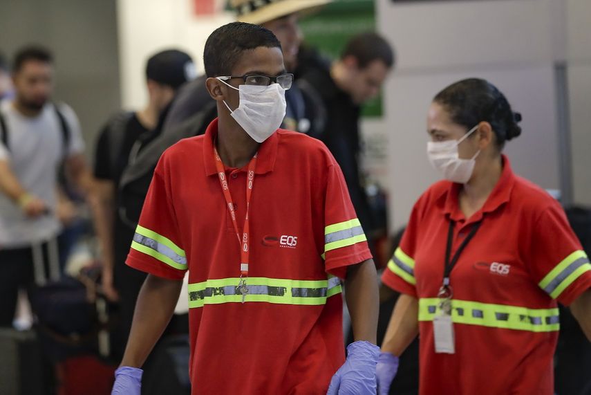 Los empleados del aeropuerto usan m&aacute;scaras como precauci&oacute;n contra la propagaci&oacute;n del nuevo coronavirus COVID-19 mientras trabajan en el Aeropuerto Internacional de Sao Paulo en Brasil, el mi&eacute;rcoles 26 de febrero de 2020.&nbsp;