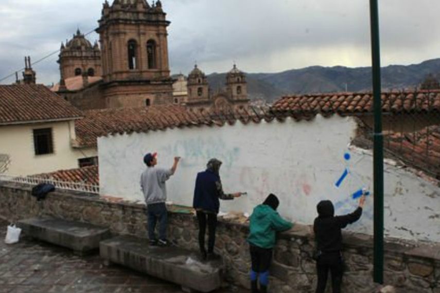 Los extranjeros que pintaron paredes patrimoniales en Cuzco realizando el repintado para tachar graffitis.