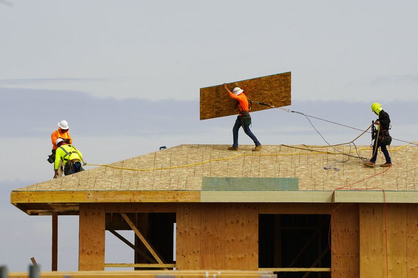 Empleados trabajan en la base del techo de una vivienda en construcción.