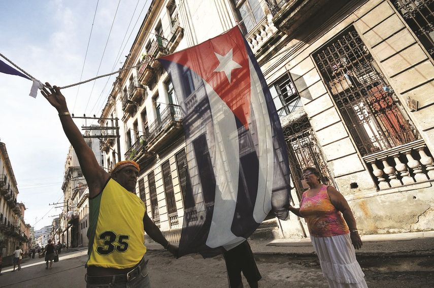 Varios cubanos en La Habana colocan una bandera durante una celebración de barrio.